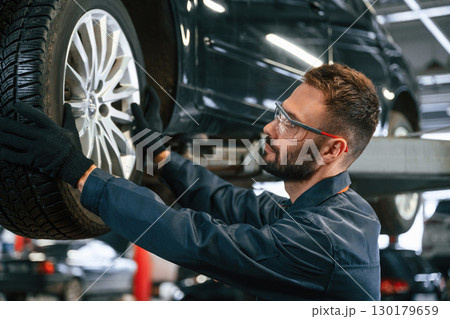 Fixing broken vehicle. Car repairman is in the garage with automobile Fixing broken vehicle. Car repairman is in the garage with automobile 130179659