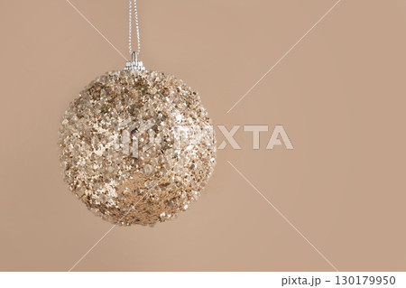 Christmas golden bauble on beige. Xmas card. 130179950