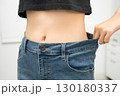 Young Asian woman losing weight wearing loose pants in oversize jeans. 130180337