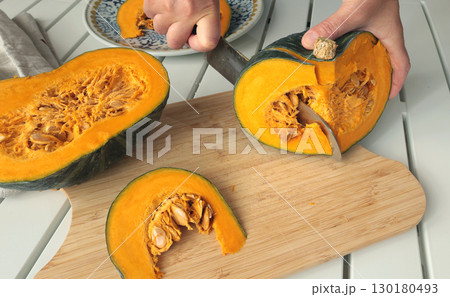 Anonymous cut pumpkin on wooden board. Farm products and healthy eating. Seasonal food, vegetarian dish. Anonymous cut pumpkin on wooden board. Farm products and healthy eating. Seasonal food, vegetarian dish. 130180493