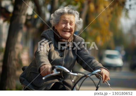 Joyful senior woman enjoying a bike ride through a park on a sunny day 130180652