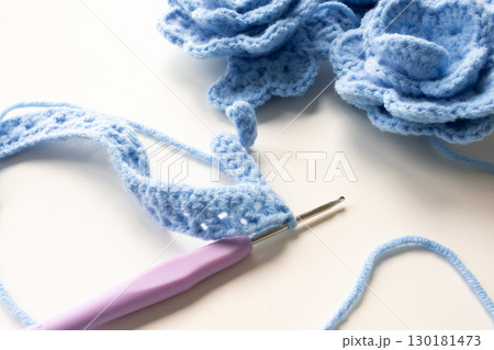 Blue crochet flowers and hook with yarn in creative craft setting Blue crochet flowers and hook with yarn in creative craft setting 130181473
