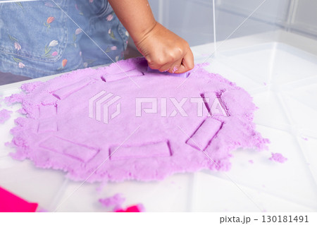 Child engaging in creative play with pink kinetic sand 130181491