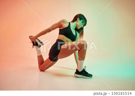 Stretching exercises. Young woman in fitness clothes is in the studio 130181514