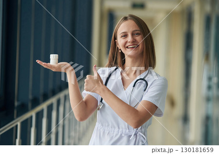 Holding prescription medicals. Female doctor in white coat is in the hall Holding prescription medicals. Female doctor in white coat is in the hall 130181659