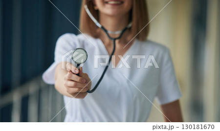 Using stethoscope. Female doctor in white coat is in the hall Using stethoscope. Female doctor in white coat is in the hall 130181670