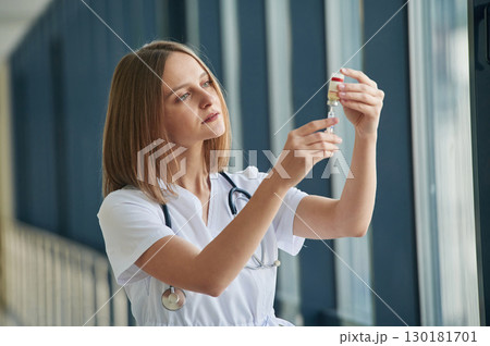 Vaccination medicine and syringe. Female doctor in white coat is in the hall Vaccination medicine and syringe. Female doctor in white coat is in the hall 130181701
