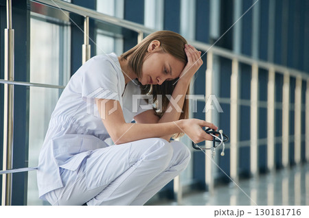 Tired, feeling bad, exhausted. Female doctor in white coat is in the hall 130181716