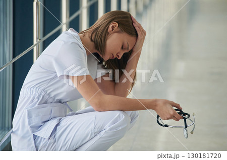 Sitting, taking a break, tired. Female doctor in white coat is in the hall 130181720