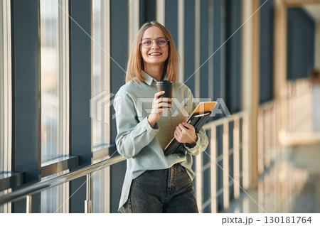 Drink, notepad and tablet in hands. Young woman in airport hall Drink, notepad and tablet in hands. Young woman in airport hall 130181764