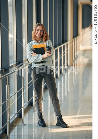 Drink, notepad and tablet in hands. Young woman in airport hall 130181765
