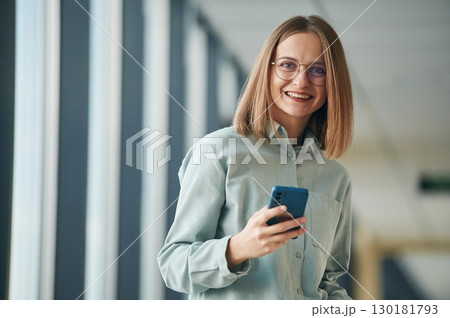 Looking at the camera, standing. Young woman in airport hall 130181793