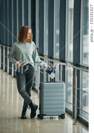 In corridor with tickets and luggage bag. Young woman in airport hall In corridor with tickets and luggage bag. Young woman in airport hall 130181827