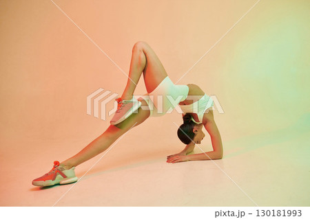 Head under the body, flexible. Young fitness woman in sportive clothes against background in studio 130181993