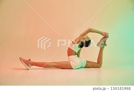 Makes twine. Young fitness woman in sportive clothes against background in studio Makes twine. Young fitness woman in sportive clothes against background in studio 130181998
