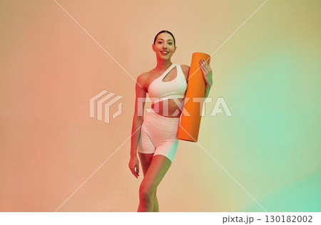 Looking forward. Young fitness woman in sportive clothes against background in studio 130182002