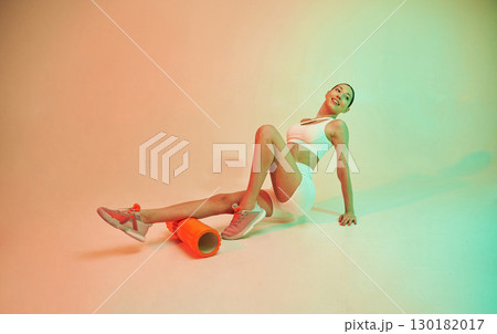 Using roller. Young fitness woman in sportive clothes against background in studio 130182017
