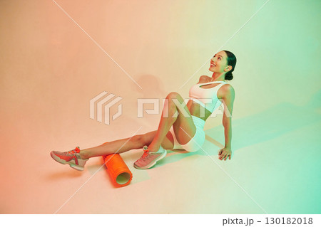 With roller. Young fitness woman in sportive clothes against background in studio 130182018