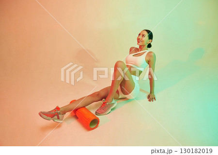 With roller. Young fitness woman in sportive clothes against background in studio With roller. Young fitness woman in sportive clothes against background in studio 130182019