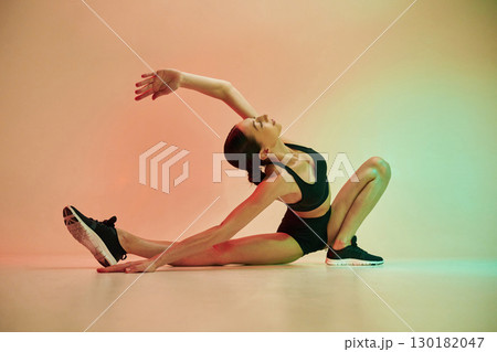 Showing flexibility. Young fitness woman in sportive clothes against background in studio Showing flexibility. Young fitness woman in sportive clothes against background in studio 130182047
