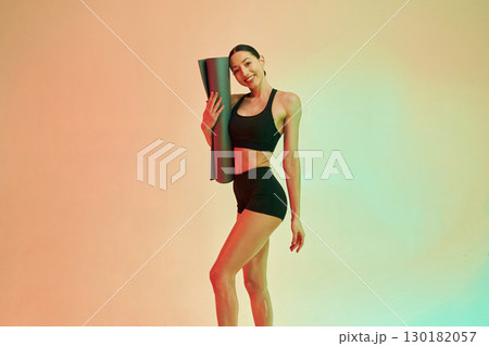 Time to practice, with yoga mat. Young fitness woman in sportive clothes against background in studio Time to practice, with yoga mat. Young fitness woman in sportive clothes against background in studio 130182057