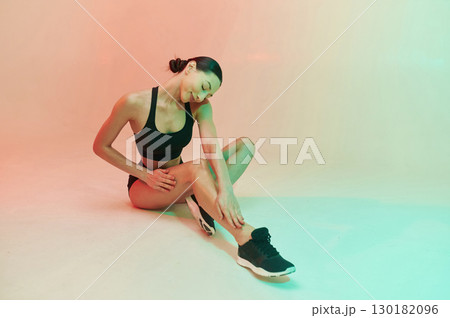 Clean legs after shaving. Young fitness woman in sportive clothes against background in studio Clean legs after shaving. Young fitness woman in sportive clothes against background in studio 130182096