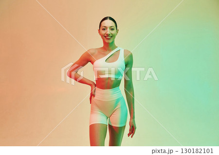 Looking forward. Young fitness woman in sportive clothes against background in studio Looking forward. Young fitness woman in sportive clothes against background in studio 130182101