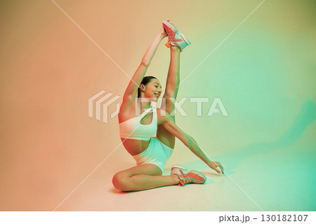 Flexible body type. Young fitness woman in sportive clothes against background in studio 130182107