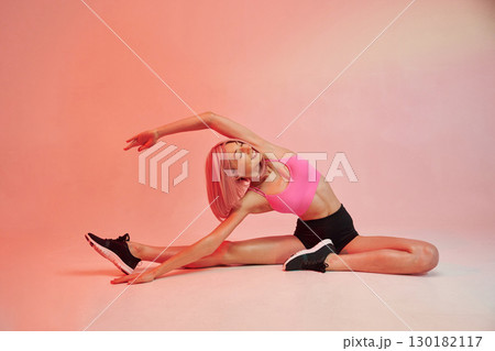 Doing yoga. Sportive woman with pink wig is against background 130182117