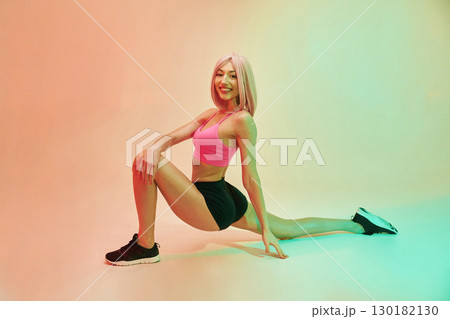 Cheerful facial expression. Sportive woman with pink wig is against background 130182130