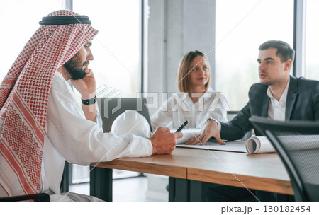 Conception of teamwork. Muslim businessman in traditional outfit with colleagues in office 130182454