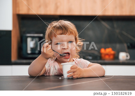 Portrait of cute little kid eating yogurt on the kitchen 130182619