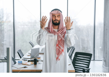 Against panoramic windows. Successful Muslim businessman in traditional outfit in his office 130182636