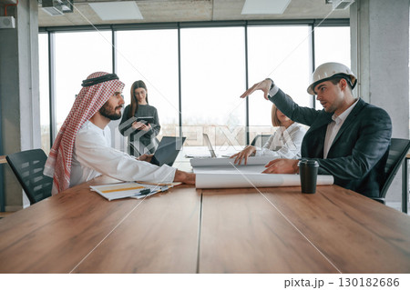 Side view. Muslim businessman in traditional outfit with colleagues in office 130182686