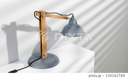 Retro or vintage style desk lamp, classic wooden arm with metal base and grey colored canopy, against white background, isolated. 130182789