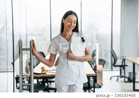 Standing and posing. Female doctor in white coat is indoors 130183408