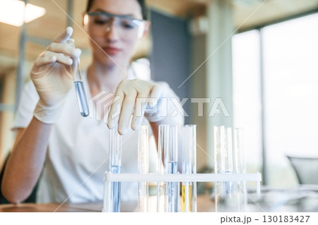 Chemical research by using liquid in test tubes. Female doctor in white coat is indoors 130183427