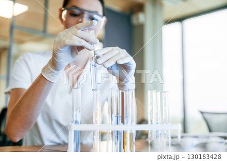 Chemical research by using liquid in test tubes. Female doctor in white coat is indoors 130183428