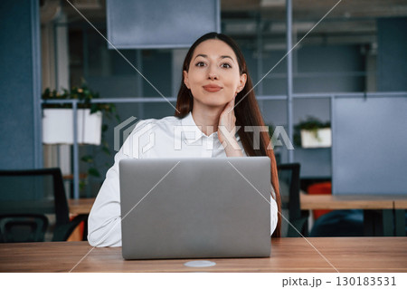 Working by using laptop. Businesswoman is indoors in the office Working by using laptop. Businesswoman is indoors in the office 130183531