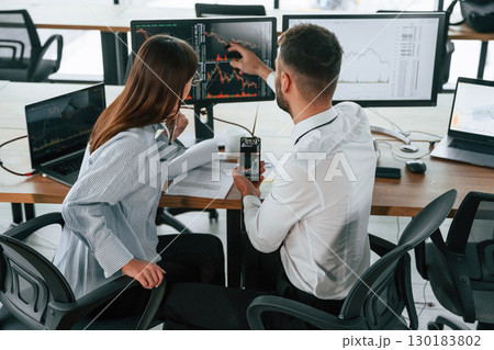 Graphs on a smartphone screen. Two employees are working in the office together 130183802