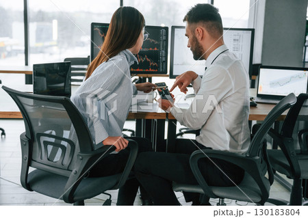 Stock information, using smartphone. Two employees are working in the office together 130183804