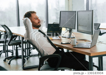 Sitting with hands behind the head. Businessman is by computer and working in the office 130183934