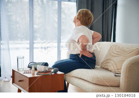 Back pain. Senior elderly woman is at home in the living room Back pain. Senior elderly woman is at home in the living room 130184018