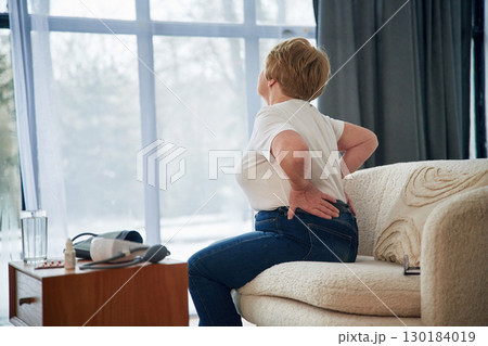 Back pain. Senior elderly woman is at home in the living room Back pain. Senior elderly woman is at home in the living room 130184019