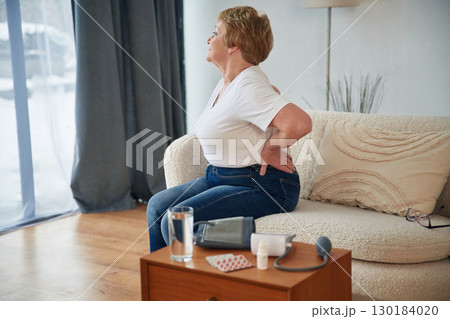 Back pain. Senior elderly woman is at home in the living room Back pain. Senior elderly woman is at home in the living room 130184020