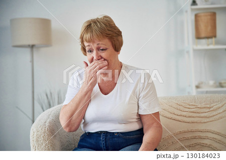 Having a cough. Feeling sick. Senior elderly woman is at home in the living room 130184023