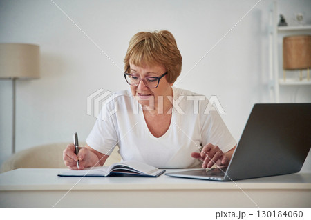 Using laptop. Senior elderly woman is at home in the living room 130184060