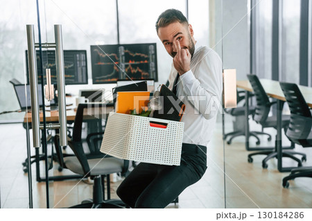 Showing middle finger. Unemployed man is with personal belongings after being fired Showing middle finger. Unemployed man is with personal belongings after being fired 130184286
