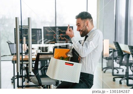 Showing middle finger. Unemployed man is with personal belongings after being fired Showing middle finger. Unemployed man is with personal belongings after being fired 130184287