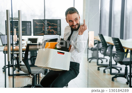 Showing middle finger. Unemployed man is with personal belongings after being fired 130184289